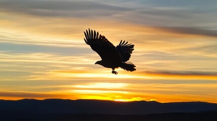 Obraz premium A silhouette of an eagle flying in the sky at sunset with mountains in the background.