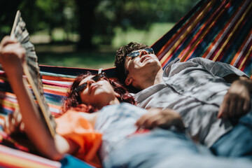 Happy couple lounging together in a colorful hammock under the sun, enjoying a relaxing day outdoors in nature.