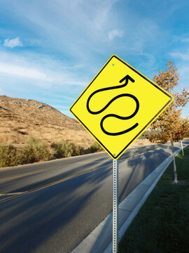 Yellow roadside warning sign with convoluted squiggly arrow.