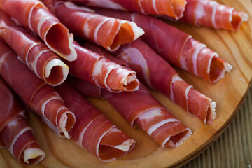 Traditional Spanish tapas - rolls of jamon serrano served on wooden board