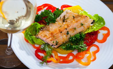 Picture of tasty fried trout fillets, served at plate with vegetables and greens..