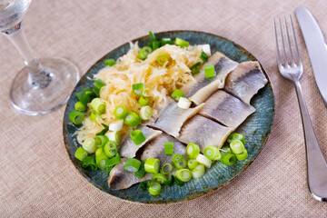 Tasty slices herring fish with pickled cabbage, served on plate