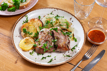 Appetizing sliced lamb leg with baked potatoes and pepper, served on platter with onion