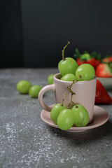 Fresh green grape in cup on dark background. Agriculture farm. Healthy eating lifestyle.