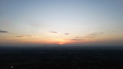 The sky is a beautiful orange color as the sun sets. The clouds are scattered throughout the sky, creating a peaceful and serene atmosphere