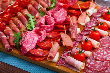 Cutting board of appetizing Spanish snack - fuet, jamon, chorizo, olives