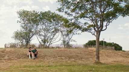 Young athletic couple relaxing in the park in summer sitting on the grass