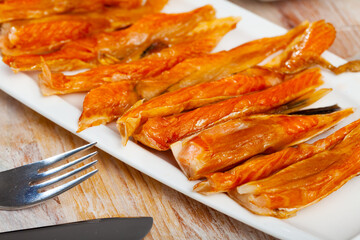Plate with smoked salmon bellies on wooden background. Fish appetizer..