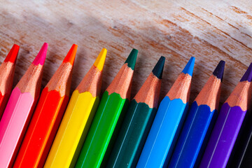 Set of multicolored pencils on wooden surface