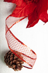 Christmas decoration detail. Red and gold Christmas decorations such as ribbon, fir branches, pine cones and Christmas tree. Background.