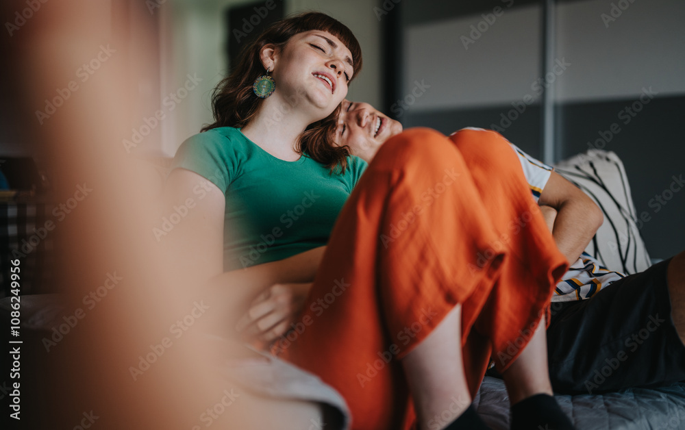 Wall mural A joyful couple enjoys a relaxing moment together on the sofa, capturing feelings of comfort and happiness at home.