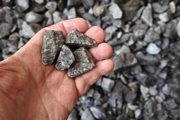 Hand holding ore mined for silver. Used in jewelry, components in electric vehicles, EVs and EV charging stations, printed circuit boards