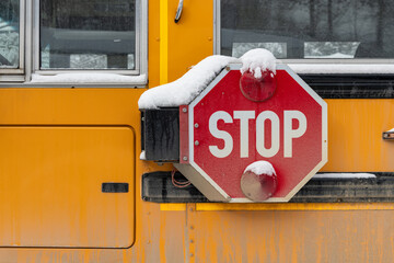 Snow covered stop arm on a school bus in winter