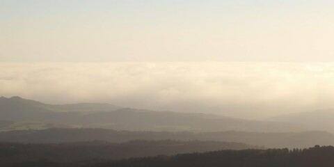 Fototapeta premium Dense fog bank hovers above vast landscape, haze, weather phenomena