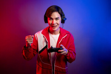 Asian young man wearing headphones, playing games in neon background.  © Pavitra
