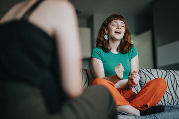 A young woman sitting cross-legged on a sofa sings with enthusiasm, displaying a joyful expression...