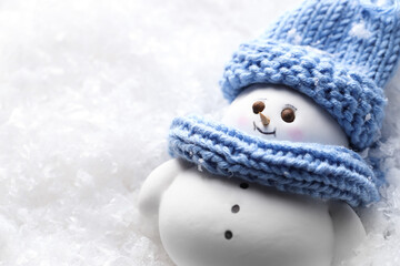 Cute decorative snowman on artificial snow, closeup. Space for text