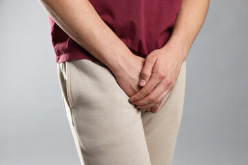 STD (sexually transmitted diseases). Man suffering from symptoms on grey background, closeup