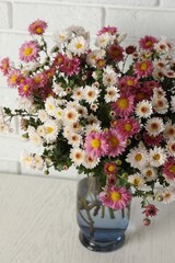 Vase with beautiful flowers on white wooden table, closeup