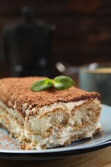 Piece of tasty tiramisu on wooden table, closeup