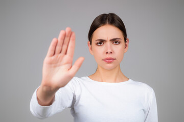 Woman with stop gesture. Young woman doing stop sign with palm of the hand. Portrait of young woman extending one hand, stop taboo sign, rejecting, declining. Girl showing stop gesture.