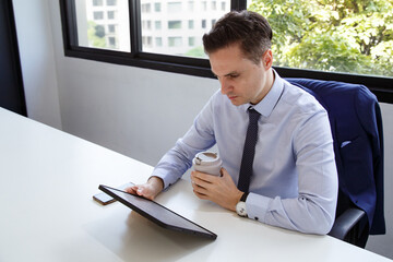 Businessman analyzing financial report and investment portfolio review on tablet. Professional mature fund broker with laptop and fact sheet of stock market and investment analysis planning