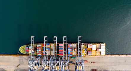 Top view of a large cargo ship loading and unloading containers at a deep sea port. Aerial view of international shipping and logistics hu