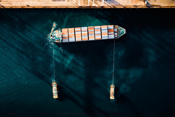 Top view of a large cargo ship loading and unloading containers at a deep sea port. Aerial view of international shipping and logistics hu