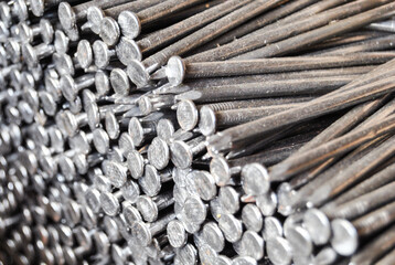 A close-up view of numerous metal nails grouped together, showcasing their shiny surfaces and sharp points. Ideal for construction, craftsmanship, and DIY projects.
