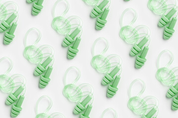 Reusable silicone green earplugs, for swim, sleep, rest as minimal trend pattern on white background. Soft, flexible ear plug on cord against noise, protect hear, top view, flat lay