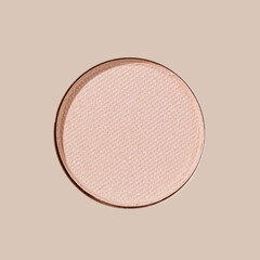 Close-up of sparkling pink beige eyeshadow round pan, pastel soft shade on beige background at...
