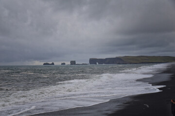 Reynisfjara black-sand beach found on the Ocean South Coast of Iceland, basalt columns and the dramatic Reynisdrangar sea stacks. Iceland, Europe.