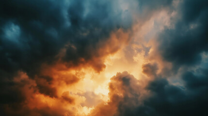 Fototapeta premium The evening sky with bursting dark storm clouds, through which golden sunlight peeks through