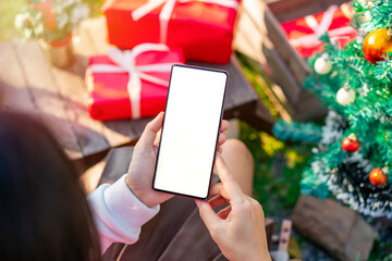 Happy young woman using smartphones with Christmas ornaments in the garden, Merry Christmas concept