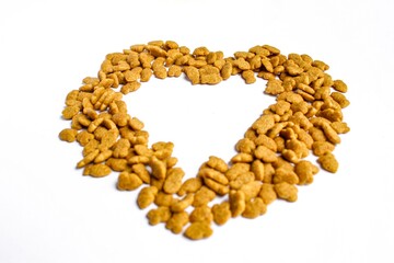 Obraz premium Pile of dry cat food in heart shape isolated on white background