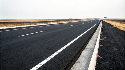 Fototapeta premium Long stretch of black asphalt road with white dividing lines and single lane traffic, solitary landscape, dark asphalt