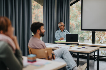 A group of students attentively listening to a senior professor during a classroom lecture, emphasizing education and learning.