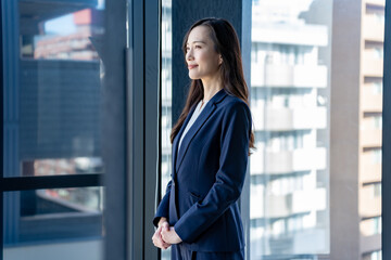 Fototapeta premium 窓を見つめるスーツを着た若い日本人女性