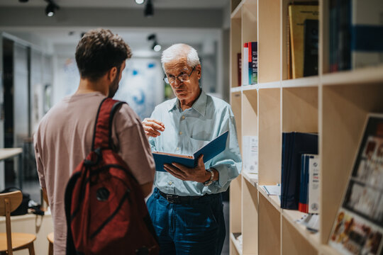A student engages in a conversation with a professor in a library, sharing knowledge and ideas. The educational atmosphere promotes learning and mentorship within an academic environment.