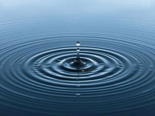 Water droplet hits surface of still lake creating concentric waves in a crown shape, clear water, waveforms