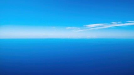 Obraz premium A sweeping vista of cerulean blue stretches out to infinity as a few wispy strands of cloud drift lazily across the horizon, serene, gentle