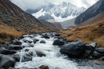 A Mountain Stream Flows Through A Valley With Snow-capped Peaks In The Distance