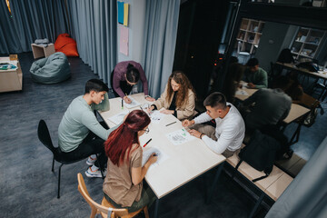 A group of students working together on a project in a contemporary classroom environment. They are focused, engaged, and using creative materials to complete their assignment.