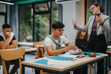 Students in a modern classroom setting attentively participate in a lecture. The atmosphere is focused and dynamic, with visible interaction between the teacher and students, highlighting education