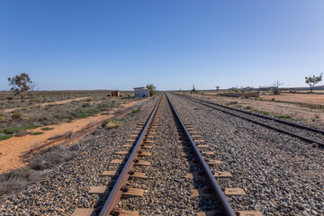 A railway track running through Olary, a shrinking village with its abandoned station and few buildings because of the declining importance of rail transport and mining ore in Eastern South Australia.