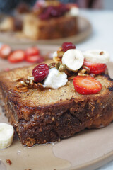 A delicious slice of banana bread topped with fresh fruits like strawberries and nuts
