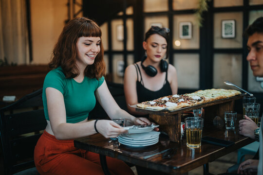 A group of friends share a large pizza at a restaurant, enjoying a casual and cheerful dining experience together. The setting is relaxed and friendly.