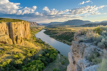 Fototapeta premium River Winding Through A Canyon With Lush Vegetation And Dramatic Clouds