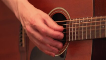 Hands strumming strings on a guitar with downstrokes, close up detail