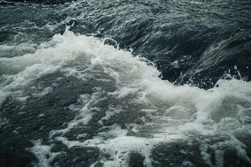 Naklejka premium Close-up of Foamy Water Rushing Over Dark Riverbed